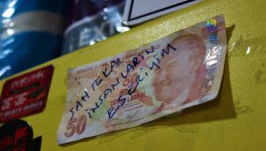 Kendisine verilen sahte parayı dükkanında sergiliyor
